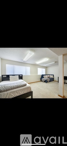 A bedroom with a bed, a chair, and a bedside table.