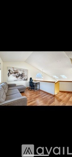 A living room with a grey sofa and a painting on the wall.