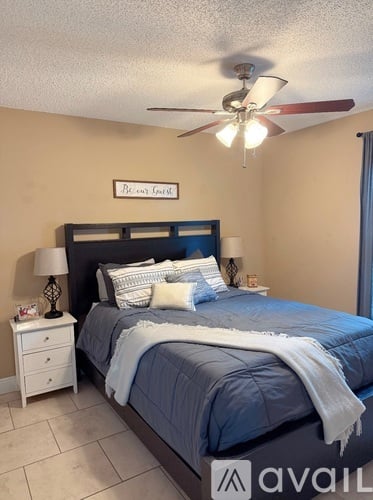 A bedroom with a bed, nightstand, and a ceiling fan.