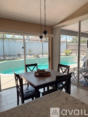 A dining room with a table and chairs and a pool in the background.