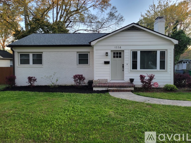 A small white house with a black roof and a grey front door.