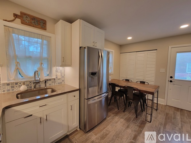 A kitchen with a refrigerator, sink, and dining table.