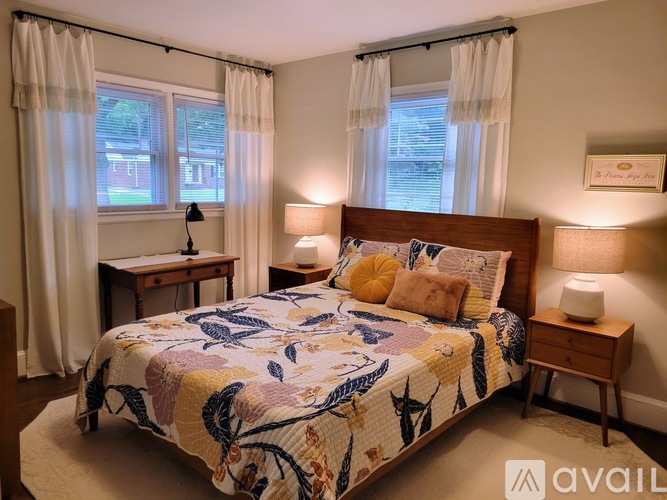 A bedroom with a large bed and a window with curtains.