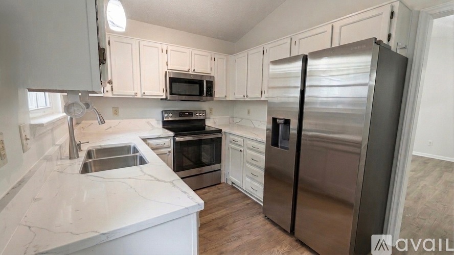 A kitchen with white cabinets and a marble countertop.