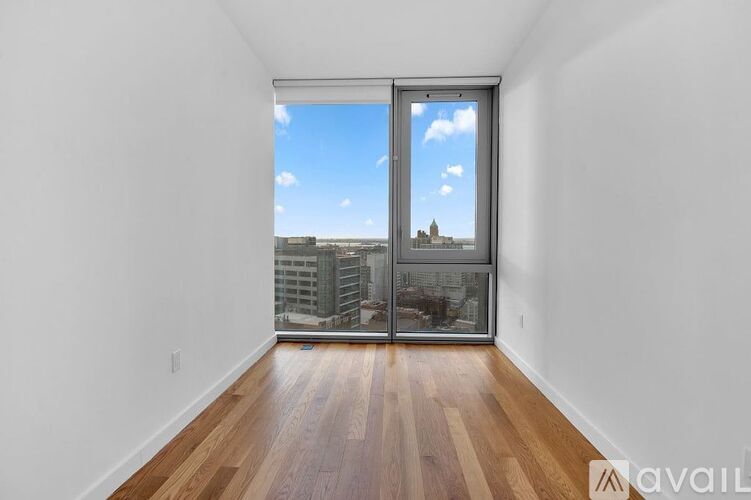 A room with wooden floors and a view of the city through a sliding glass door.