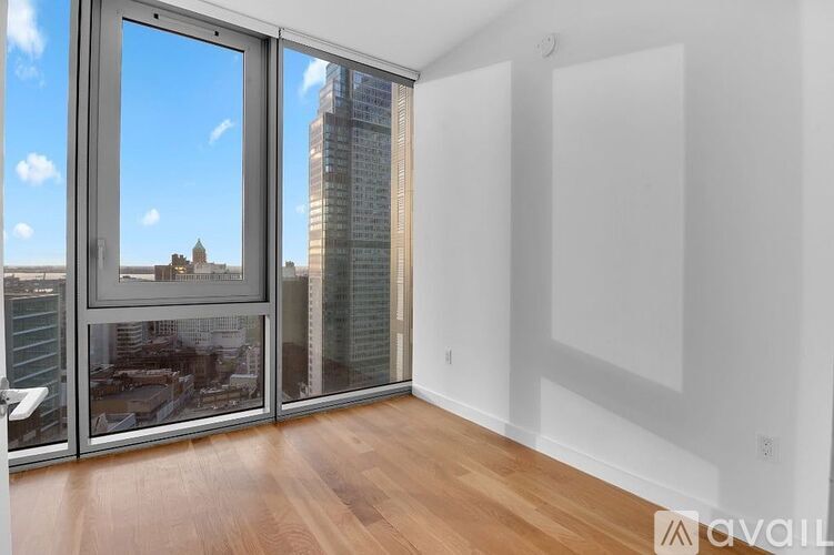 A room with a wooden floor and a large window with a view of a cityscape.
