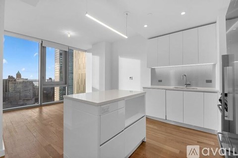 A modern kitchen with white cabinets and a wooden floor.