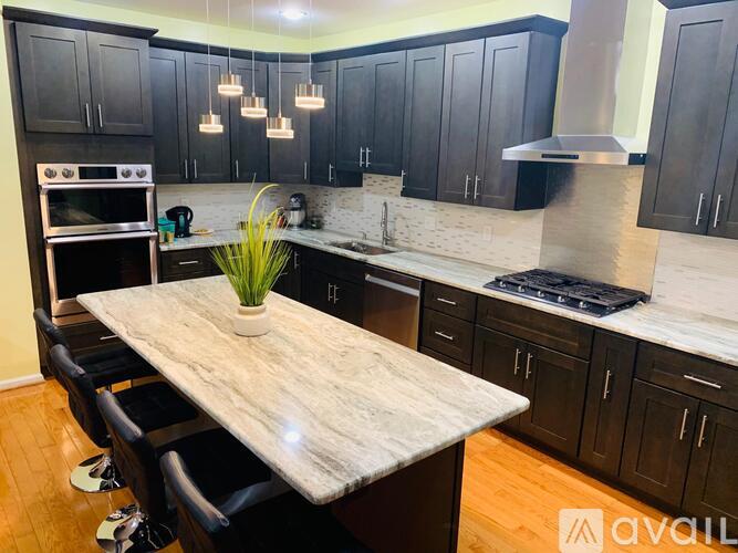 A kitchen with a marble table and black cabinets.
