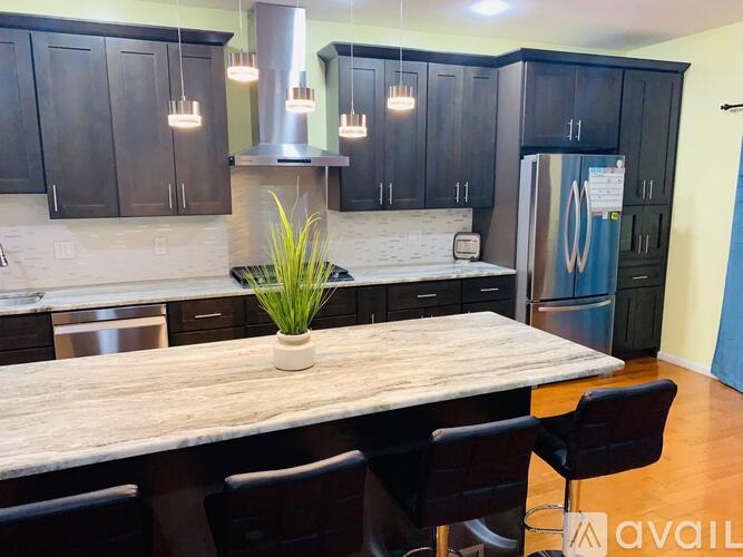 A kitchen with a marble table and black cabinets.