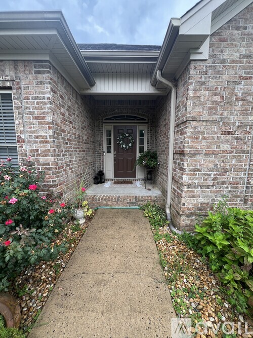 A brick house with a brown door and a small porch.