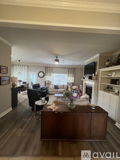 A living room with a brown cabinet and a white ceiling fan.