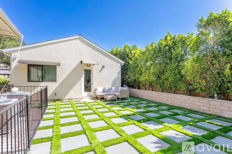 A house with a white exterior and a green and white patterned lawn in front.