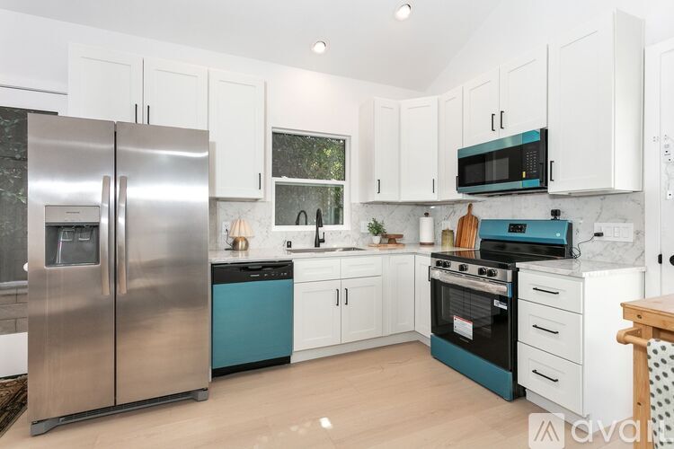 A kitchen with white cabinets and a stainless steel refrigerator.