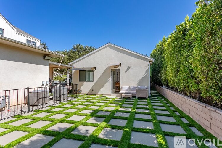 A modern house with a white exterior and a green and white tiled patio area.