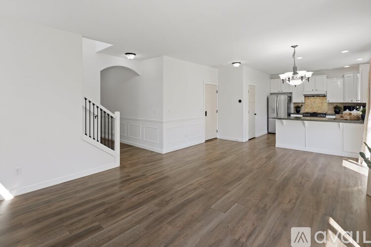 A spacious living room with wooden flooring and white walls.
