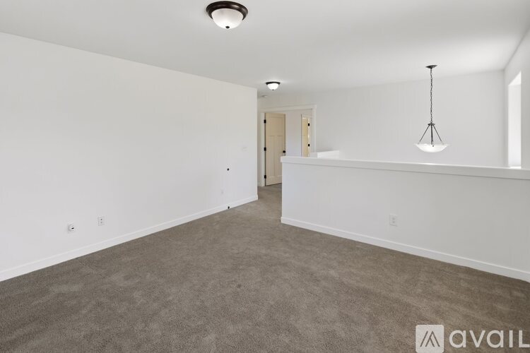 A spacious room with a carpeted floor and a hanging light fixture.