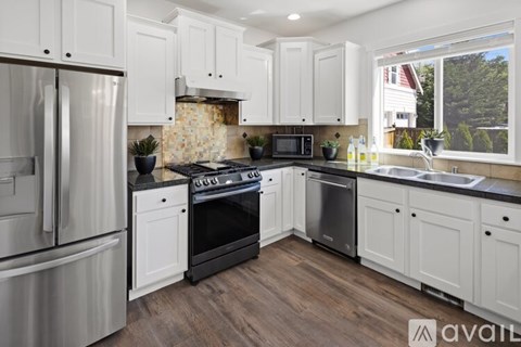 A kitchen with white cabinets and a stainless steel refrigerator.