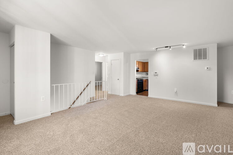 A spacious living room with a staircase and a kitchen in the background.
