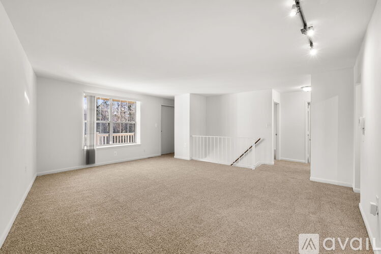 A spacious room with a carpeted floor and a staircase leading to another level.