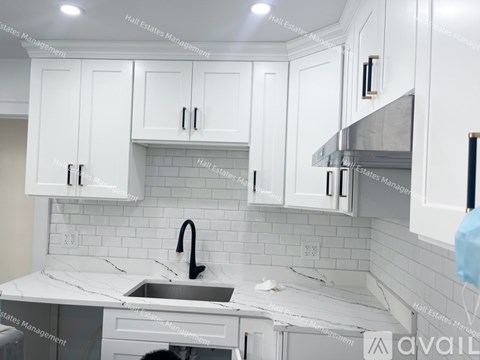 A kitchen with white cabinets and a marble countertop.