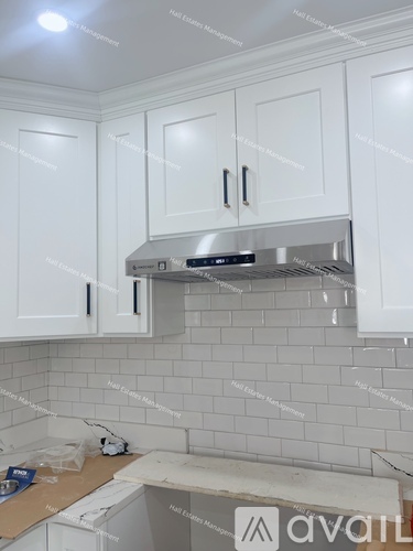 A kitchen with white cabinets and a stainless steel range hood.