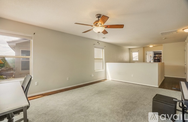 A spacious room with a ceiling fan and a carpeted floor.
