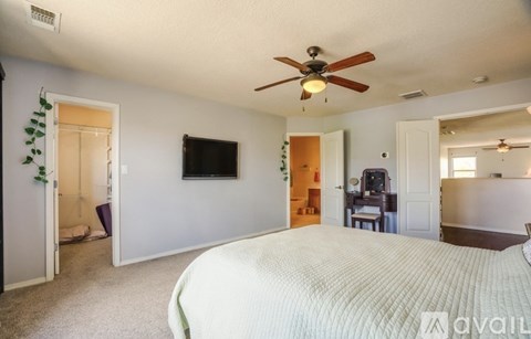 A bedroom with a large bed and a ceiling fan.