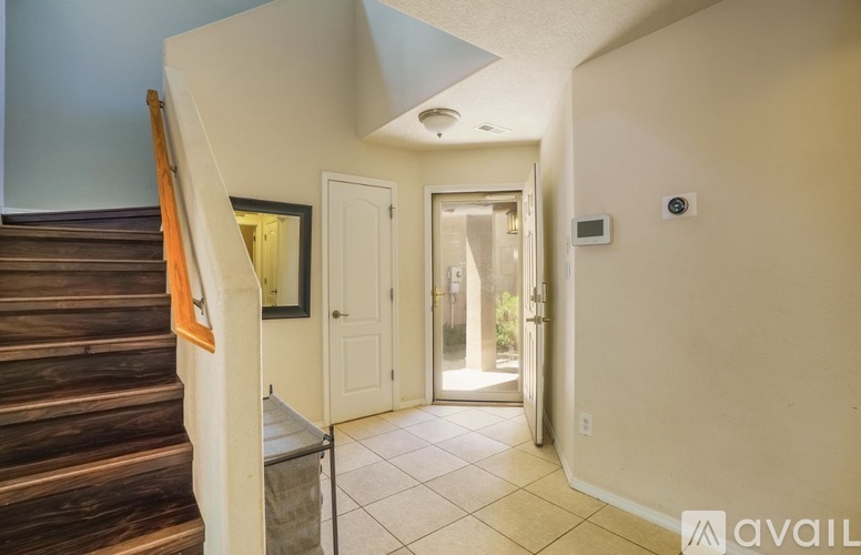 A hallway with a staircase on the left and a door on the right.