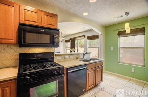 A kitchen with a black stove top oven and black microwave above a black dishwasher.