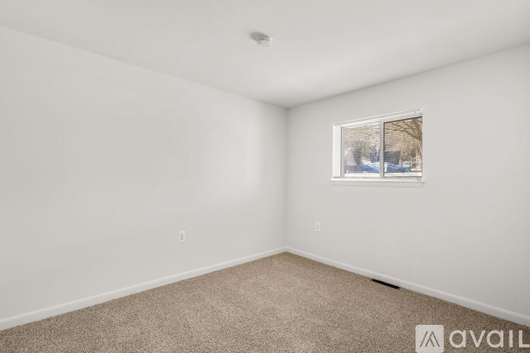 A room with a carpeted floor and a window showing a snowy scene outside.