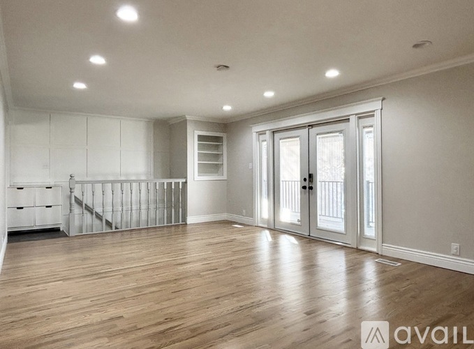 A spacious room with wooden floors and white walls.