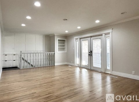 A spacious room with wooden floors and white walls.