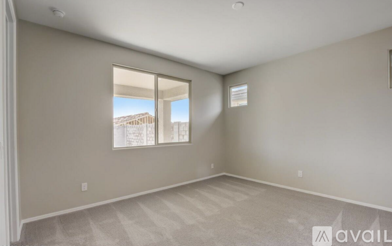 A room with a carpeted floor and a window with a view of a building outside.