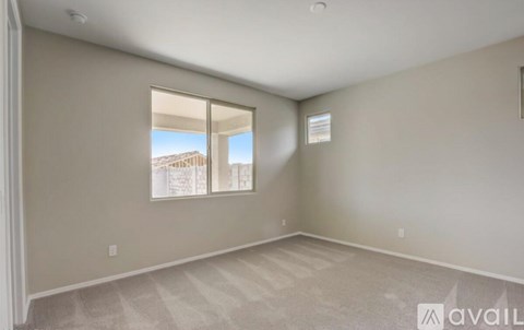 A room with a carpeted floor and a window with a view of a building outside.
