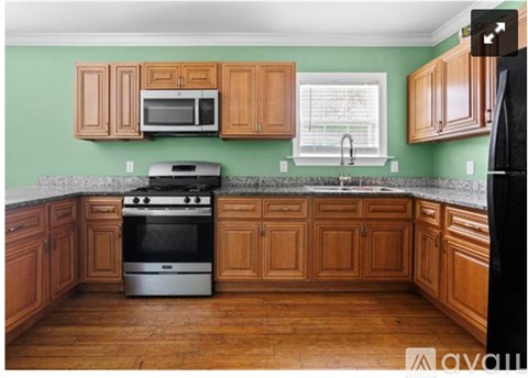 A kitchen with wooden cabinets and a black refrigerator.