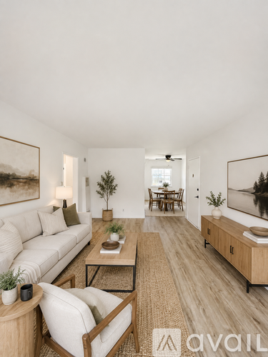 A living room with a white sofa, a wooden coffee table, and a painting on the wall.