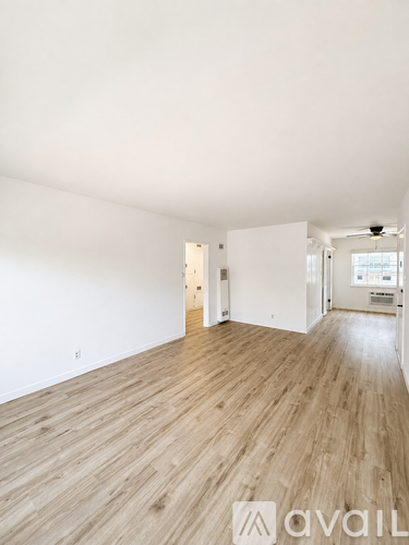 A spacious room with wooden flooring and white walls.