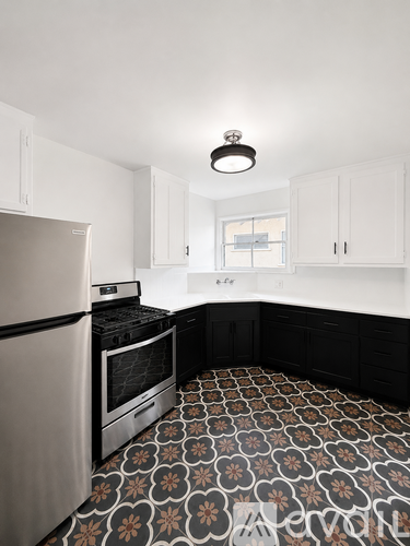 A kitchen with a patterned floor and a stainless steel refrigerator.