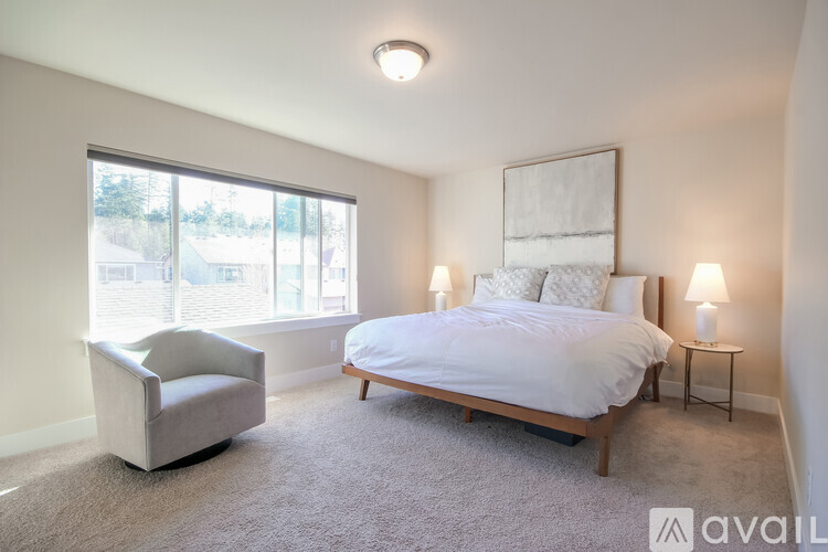 A bedroom with a large bed, a chair, and a window overlooking a street.