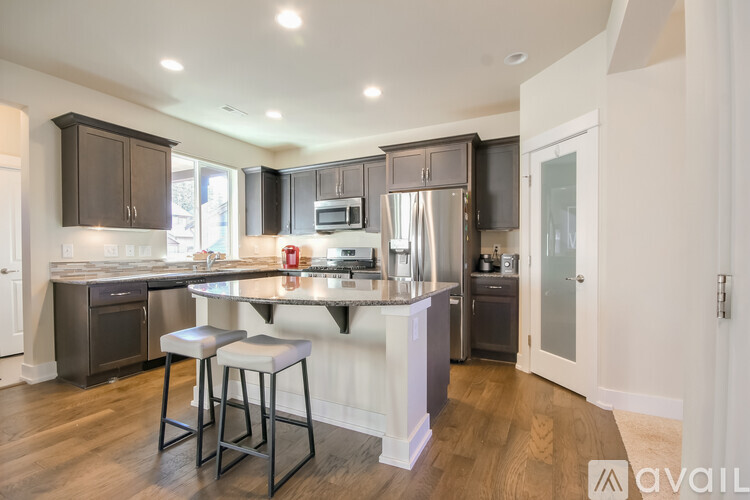 A modern kitchen with dark brown cabinets and a white island.