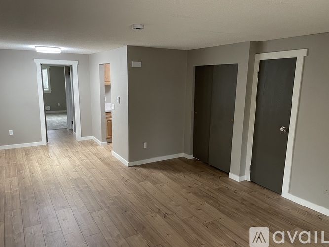 A room with wooden flooring and two doors.