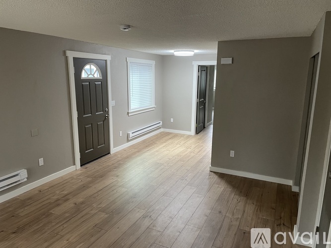 A room with wooden flooring and a door with a stained glass window.