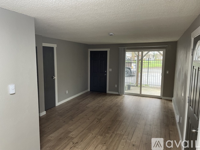 A room with wooden floors and a sliding glass door leading to a balcony.