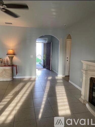 A living room with a fireplace and a lamp on the side table.