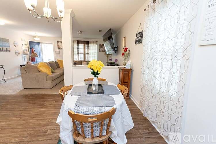 A dining room with a table set for two and a couch in the background.
