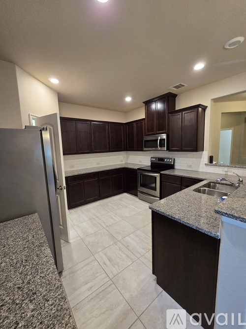 A kitchen with granite countertops and dark brown cabinets.