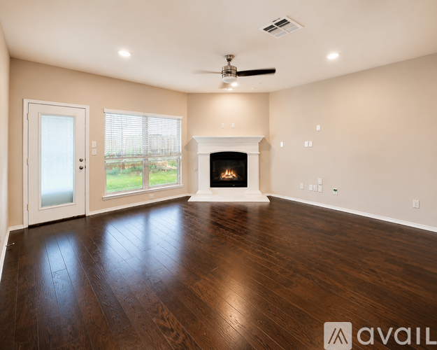 A spacious room with a fireplace and wood flooring.