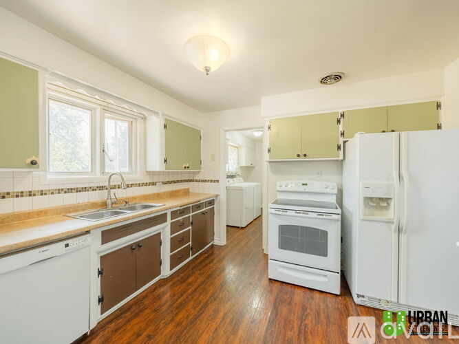 A kitchen with white appliances and wooden floors.