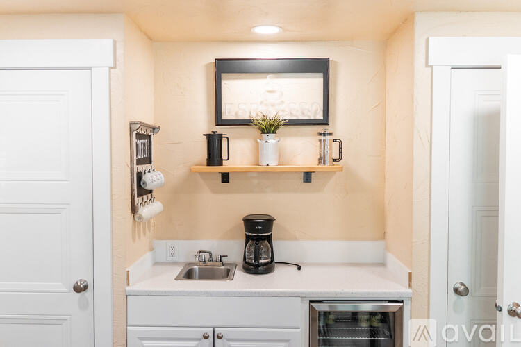 A kitchen with a sink, a coffee maker, and a framed picture on the wall.