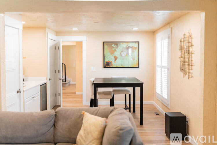 A living room with a grey couch and a painting on the wall.